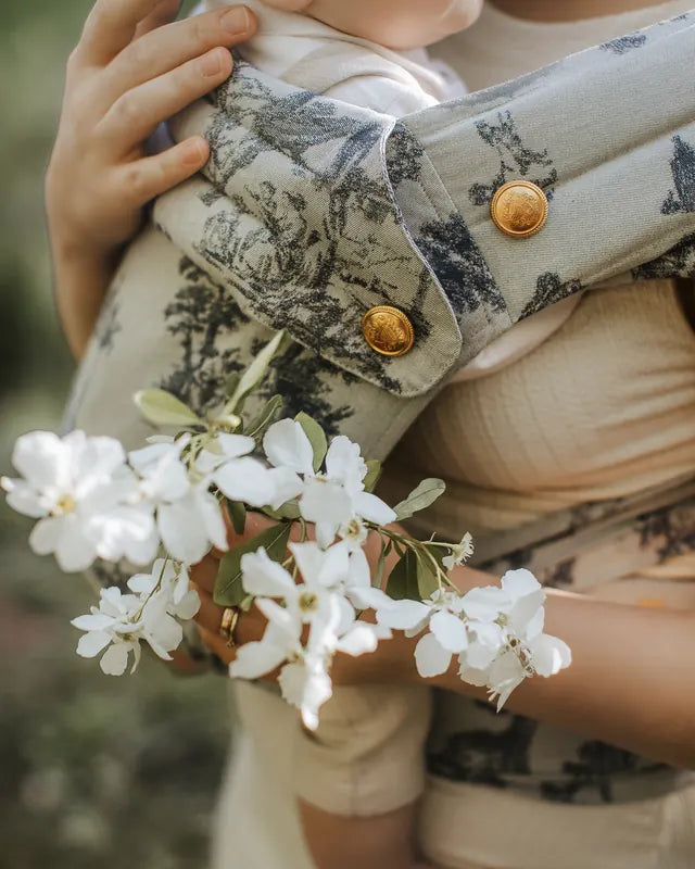 Close-up of a MonDoudou Toile de Jouy strap: woven motif, gold buttons bearing the coat of arms, a sprig of blossom in front.